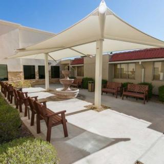 An outdoor patio area with seating under a large shade structure on a sunny day.