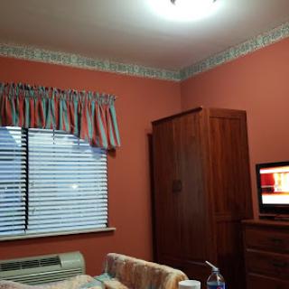 A cozy bedroom featuring a warm wall color, simple furniture, and a television.