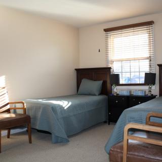 A minimalist bedroom with twin beds and simple furnishings.