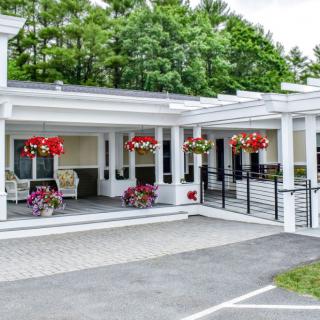A charming house with a large porch adorned with hanging flower baskets.