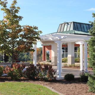 A beautifully designed pavilion surrounded by lush gardens and trees on a bright day.