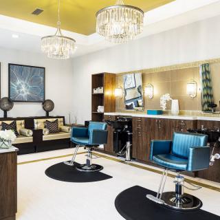 A modern, stylish salon interior with blue chairs and elegant chandeliers.