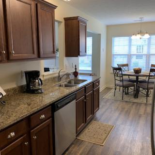 A modern kitchen featuring wood cabinets and a cozy dining area with natural light.