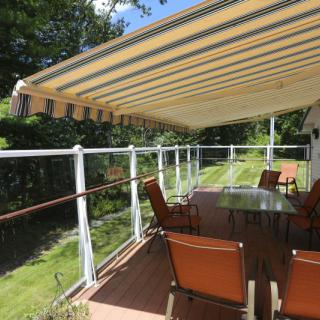A cozy patio with a striped awning providing shade over outdoor furniture on a wooden deck.