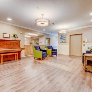 A cozy lounge area featuring a wooden piano, plush chairs, and ambient lighting.