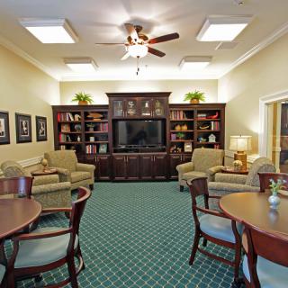 A cozy living room with seating, a bookshelf, and a large television.