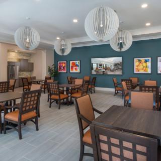 A modern dining area with neatly arranged tables and chairs, complemented by stylish lighting and vibrant wall art.