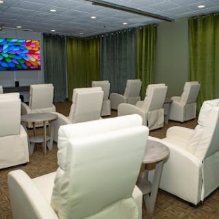 A modern lounge area featuring comfortable recliner chairs and a large TV, designed for relaxation.