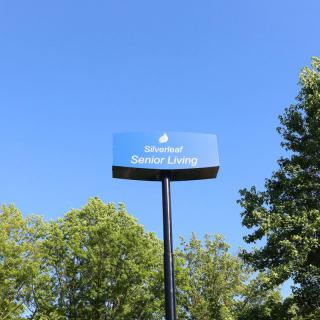 A parking sign for senior living against a clear blue sky, surrounded by trees.