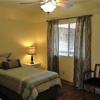 A cozy bedroom with a single bed, lamp, and window with curtains.