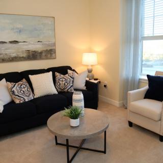 A cozy living room with a dark sofa, armchair, and soft lighting.