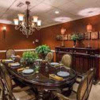 A warmly lit, elegant dining room with a chandelier and a set dining table.
