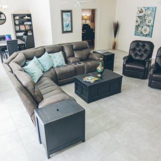 A spacious living room featuring a large sectional sofa, two armchairs, and a coffee table.