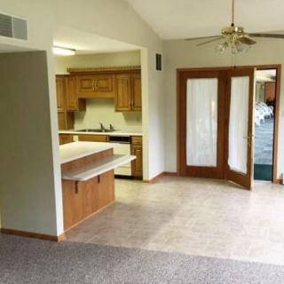 Open kitchen and living area with wood cabinets and French doors leading outside.