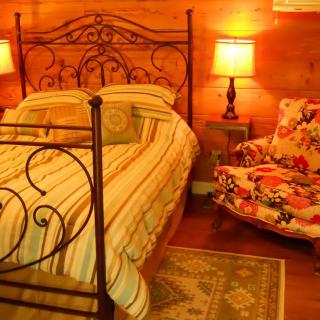 A cozy bedroom with a wrought iron bed, warm lighting, and wooden walls.