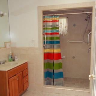 A bright and colorful bathroom featuring a shower with a striped curtain and a wooden vanity.