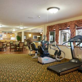 A spacious gym area with fitness equipment and a carpeted floor.