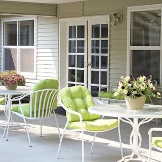 A cozy patio with green-cushioned chairs and flowers.
