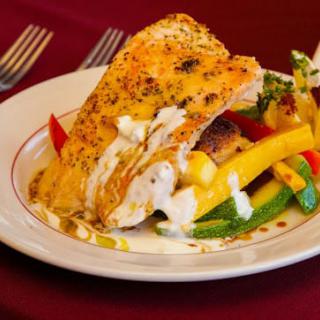 A delicious plate of roasted chicken served with seasoned vegetables and topped with a creamy sauce.