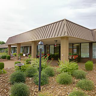 A modern building with a landscaped garden in front, featuring large windows and a triangular roof.