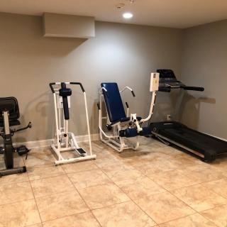 A home gym with various exercise equipment including a treadmill and workout machines.