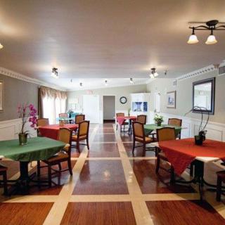A spacious and well-decorated dining room with multiple tables and chairs, featuring elegant lighting and polished wooden flooring.