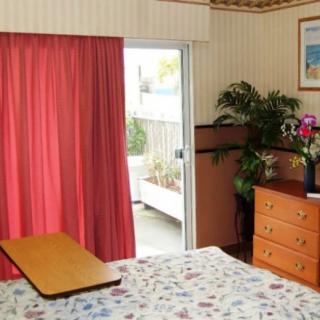 A cozy bedroom with a dresser, plants, and red curtains.