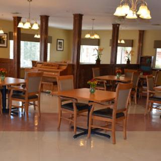 A cozy dining area featuring wooden tables and chairs, with warm lighting creating an inviting atmosphere.