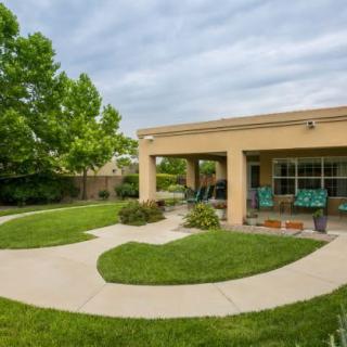 A serene backyard patio with a well-maintained lawn and surrounding trees.