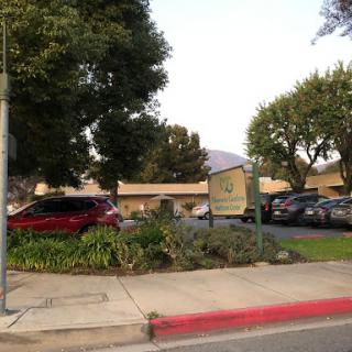 A view of a building with a sign and surrounding greenery in the parking area.