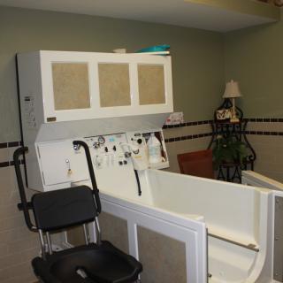 A healthcare facility room featuring a specialized bathtub with an attached chair for assisted bathing.
