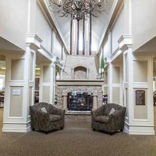 A spacious lobby featuring a grand fireplace and elegant chandelier with two comfortable armchairs.
