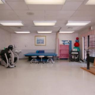 A physical therapy room equipped with exercise machines and a treatment table.