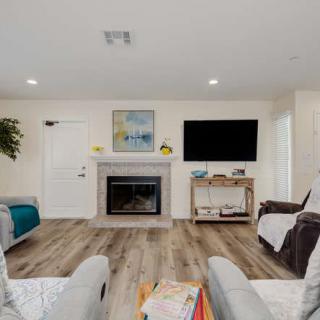 A modern living room featuring a cozy fireplace, large television, and stylish wood flooring.