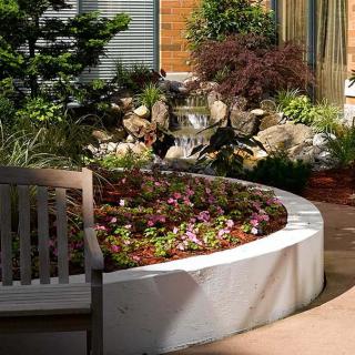 A beautifully landscaped garden with a circular flower bed and a wooden bench.