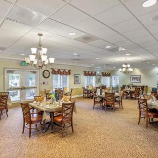 Spacious dining area with multiple tables and chairs, adorned with elegant chandeliers and large windows.