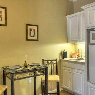 A cozy kitchen corner with a small dining table and chairs next to white cabinets.