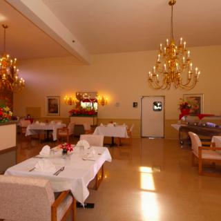 An elegant restaurant dining room with chandeliers and neatly arranged tables.