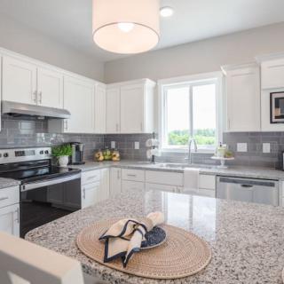 A modern kitchen with white cabinets, granite countertops, and stainless steel appliances.