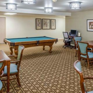 A game room with a billiard table, seating area, and computer station.