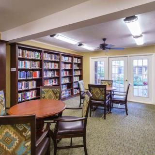 A cozy library room with bookshelves, tables, and chairs.