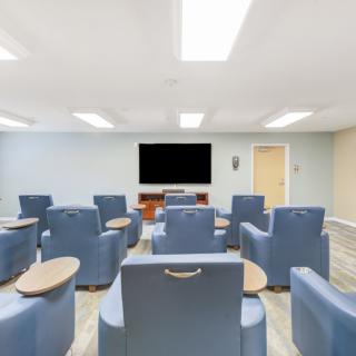 A modern conference room featuring comfortable seating and a large television screen.