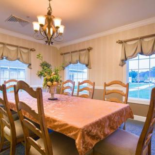 A warmly lit dining room with a large table, chairs, and elegant decor.