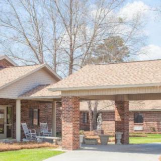 A brick residential building with a porch and outdoor seating.