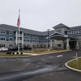 A large building with a prominent entrance and an American flagpole in the foreground.