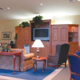 A cozy living room with a sofa, armchair, television, and a lamp on a side table.