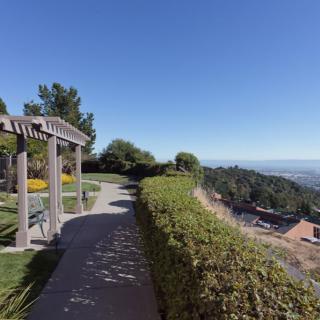 A scenic garden pathway with a pergola overlooking a vast landscape.