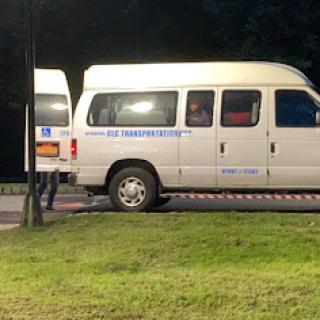 A white van parked in a grassy area at night.