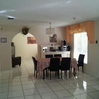 A well-lit dining room with a table and chairs on a tiled floor.