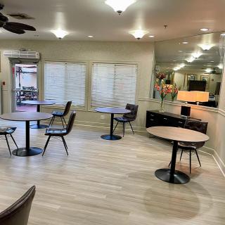 A modern dining area with tables and chairs arranged on wooden flooring and bright lighting.